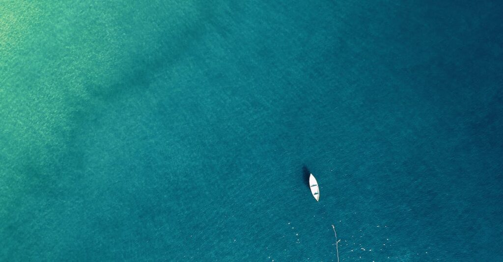 Aerial view of a lone boat on calm turquoise waters, showcasing tranquility.